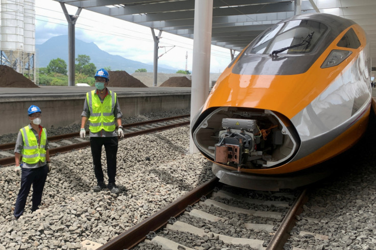 Workers stand beside an Electric Multiple Unit high-speed train for a rail link project part of China's Belt and Road Initiative, at Tegalluar train depot in Bandung