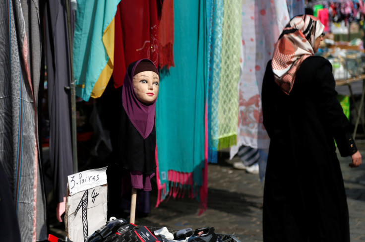 A woman walks past a mannequin wearing an hijab headscarf at a market in the Brussels district of Molenbeek