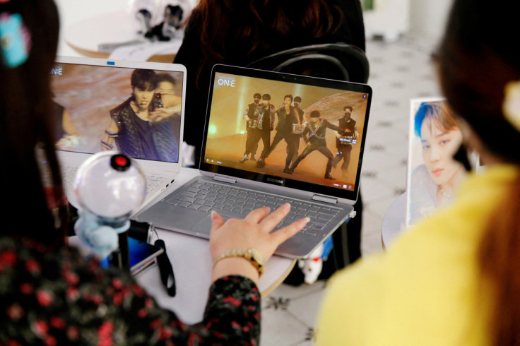 Fans of K-pop idol boy band BTS watch a live streaming online concert, wearing a protective masks at a cafe, in Seoul