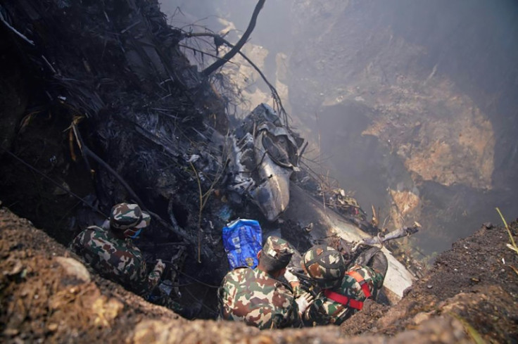 Rescuers inspect the site of a plane crash in Pokhara, Nepal