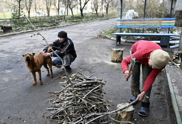 Residents Lydmyla (R) and Ruslan chop branches for firewood in Avdiivka