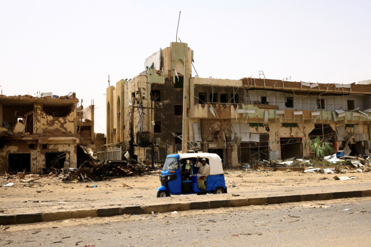 People pass by damaged cars and buildings at the central market in Khartoum North