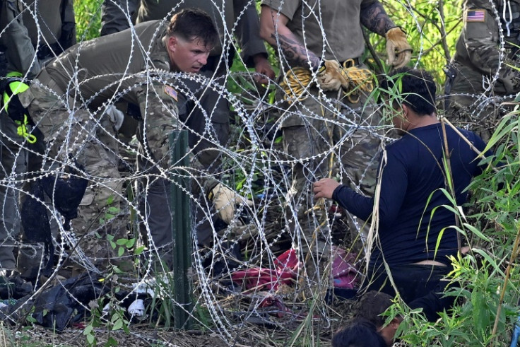 A migrant who crossed the Rio Grande is detained by US National Guardsmen reinforcing a barbed wire fence along the river on the US-Mexico border, seen from Matamoros, Tamaulipas state, Mexico, on May 10, 2023