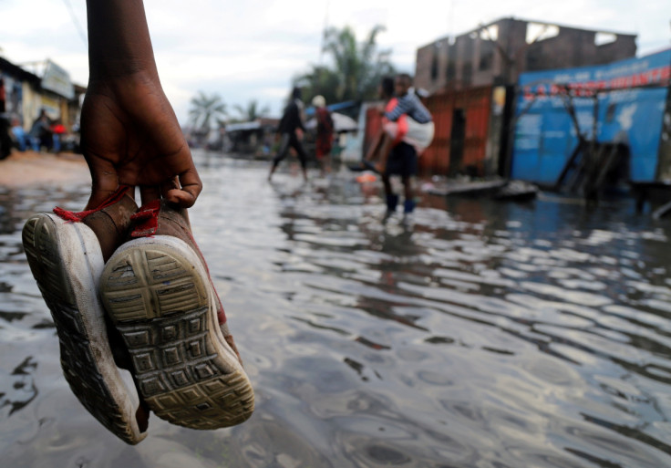 A Congolese man carries his shoes as he wades through floodwaters along a street in Kinshasa
