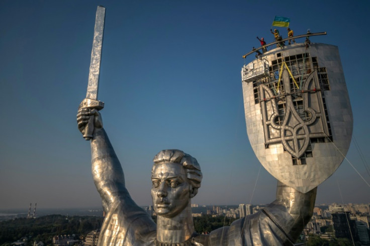 Workers lowered the hammer and sickle from the Soviet emblem that originally decorated the shield on Tuesday