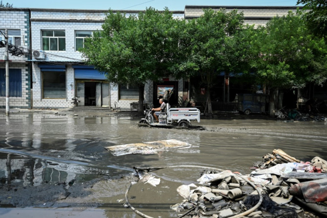 A man drives along a flooded street in the aftermath of flooding from heavy rains in Zhuozhou city, in northern China's Hebei province on August 9, 2023