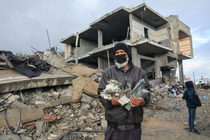 A Palestinian man carries books salvaged from the rubble following an Israeli strike in Rafah in the southern Gaza Strip