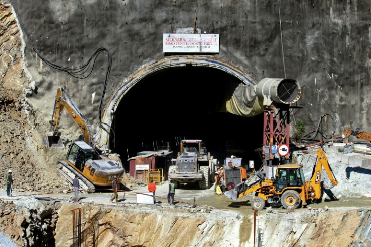 Rescue workers stand at an entrance of the under-construction road tunnel, days after it collapsed