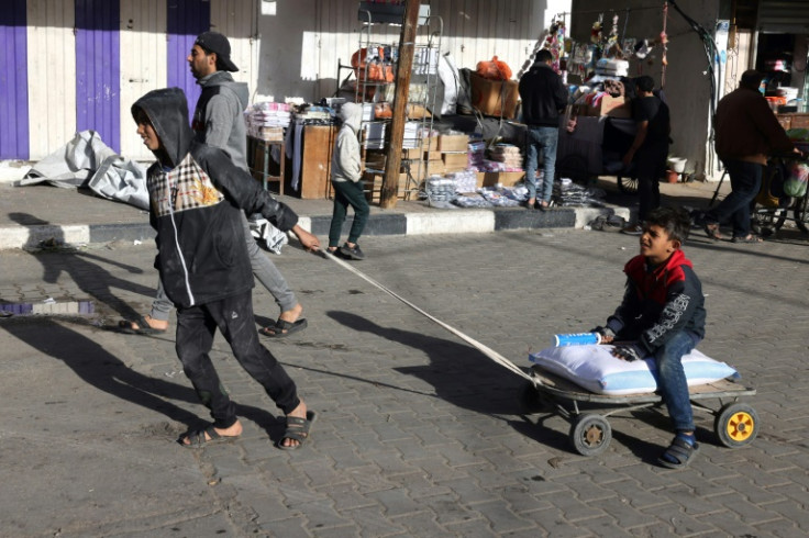 A Palestinian boy pulls another child and a sack of food in Rafah, the southern Gaza Strip