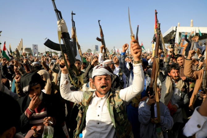 Huthi fighters brandish their weapons during a protest in the rebel-held capital, Sanaa, on Friday
