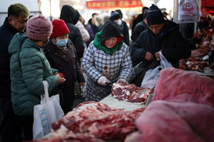 A vendor cuts meat for customers at a market in Shenyang, in China's northeastern Liaoning province in January