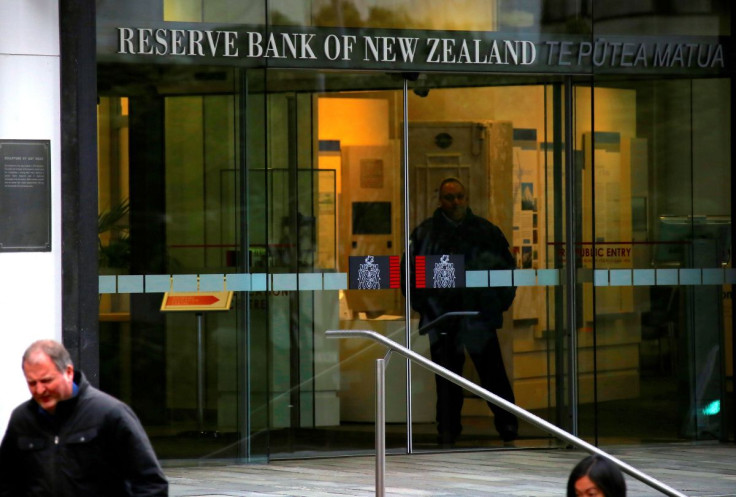 Pedestrians walk past as a security guard stands in the main entrance to the Reserve Bank of New Zealand located in central Wellington, New Zealand, July 3, 2017.