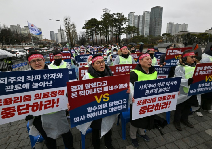 Doctors hold placards reading "Stop populist medical policy!" during a protest in Seoul on February 21, 2024