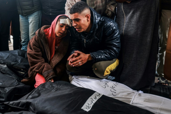 An injured girl and a man at Rafah's Al-Najjar hospital mourn over the bodies of relatives killed in Israeli bombardment