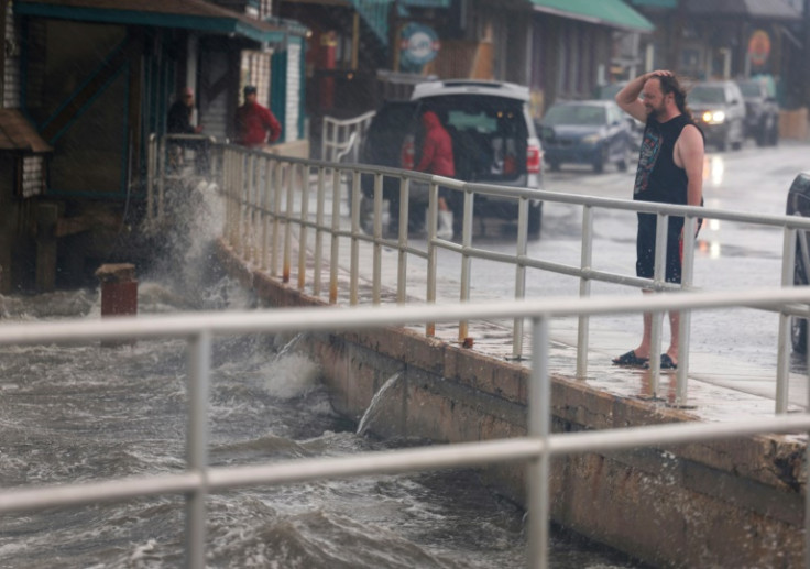 A rain-soaked man in Cedar Key, Florida observes waves kicked up by the winds of Tropical Storm Debby, which is strengthening as it moves through the Gulf of Mexico on August 04, 2024