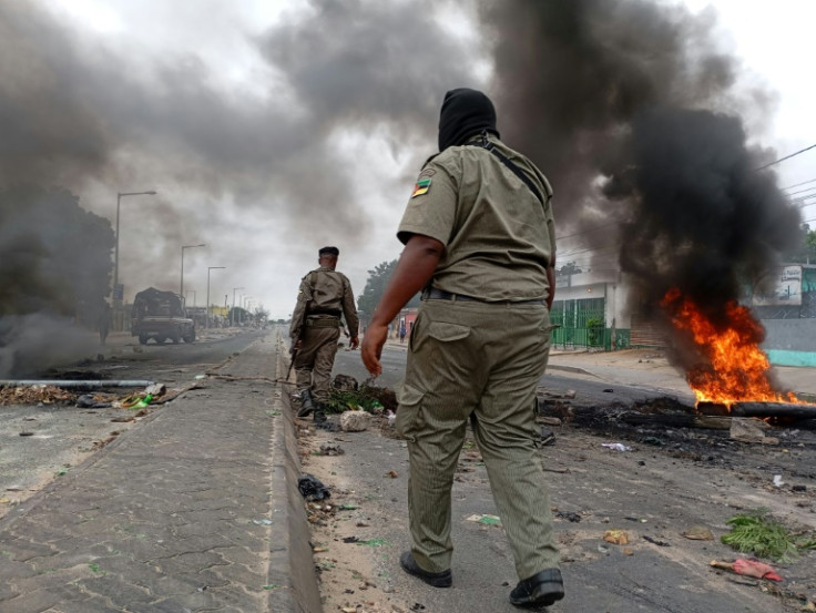 Mozambican security forces next to a burning barricade in Maputo on Tuesday
