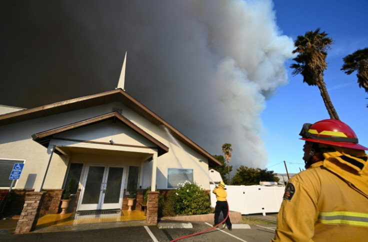 California firefighters protect a church as the plume of smoke from the Hughes fire darkens the sky